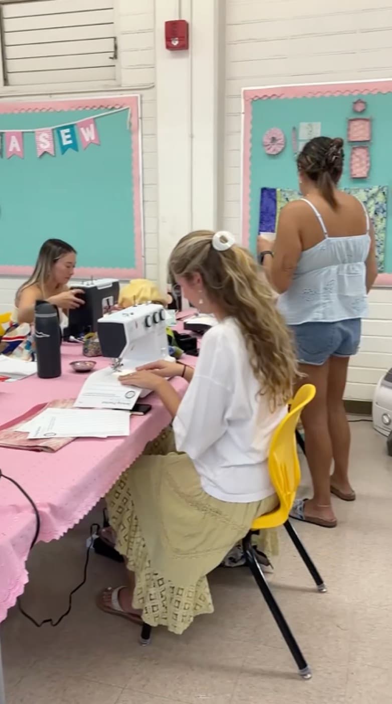 Sewing class in session with students at pink-covered tables